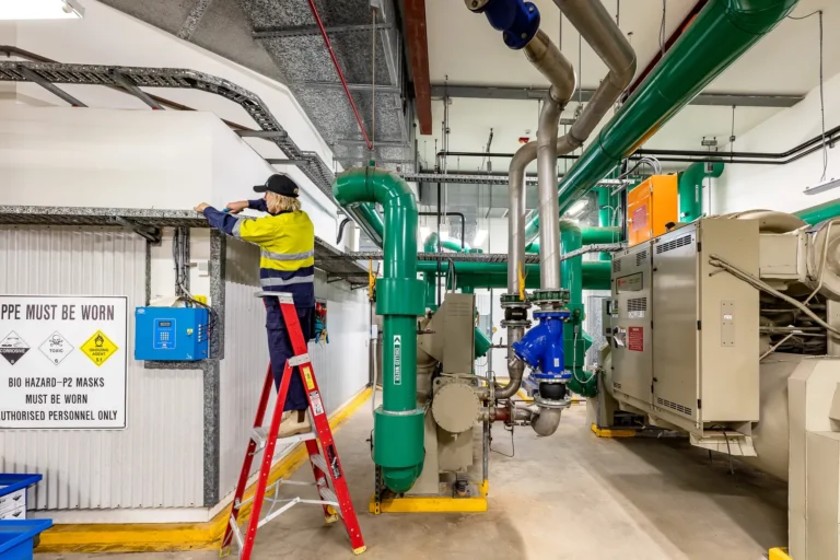 Technician working in an industrial facility with green pipes.