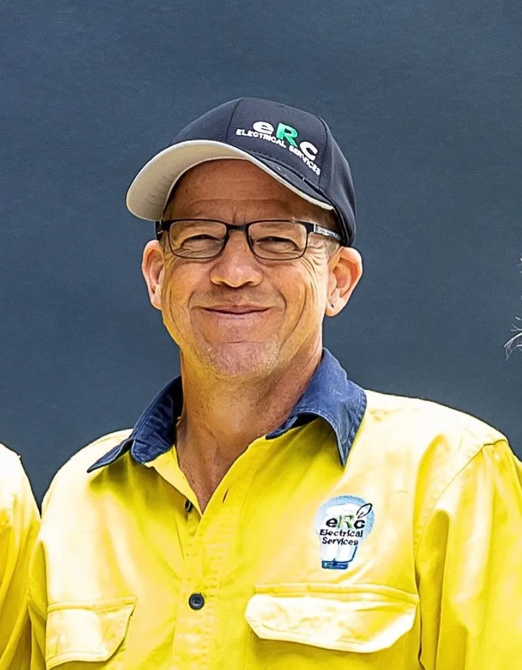 Man in yellow "Electrical Services" uniform smiling.
