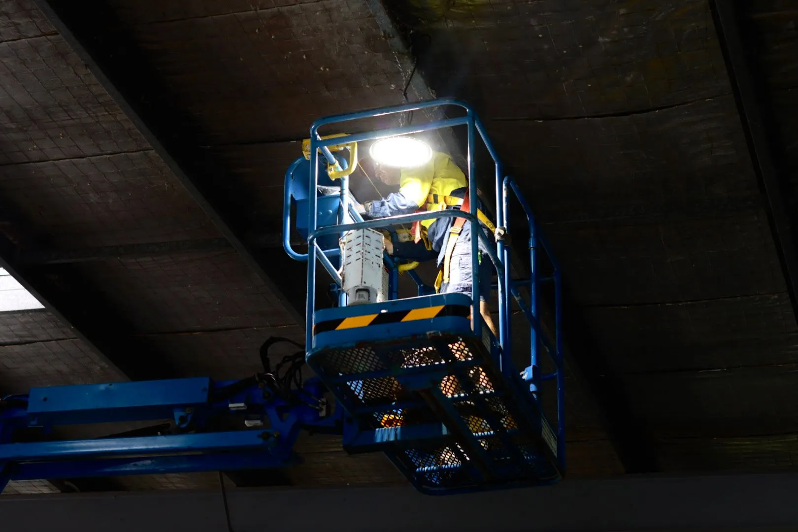 Maintenance worker in a hydraulic lift repairing ceiling lights.